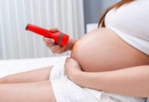 Botched Denominator Sparks Miscarriage Scare Pregnant woman shining flashlight on bare belly
