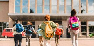 Group of schoolchildren with backpacks running toward a school entrance
