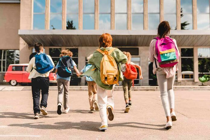 shutterstock_2040833939 Group of schoolchildren with backpacks running toward a school entrance