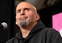 bald man with goatee speaking at a microphone