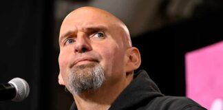 bald man with goatee speaking at a microphone