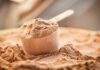 Whey Boom Hijacks Dairy — Farmers Squeezed Scoop of chocolate protein powder in a measuring cup