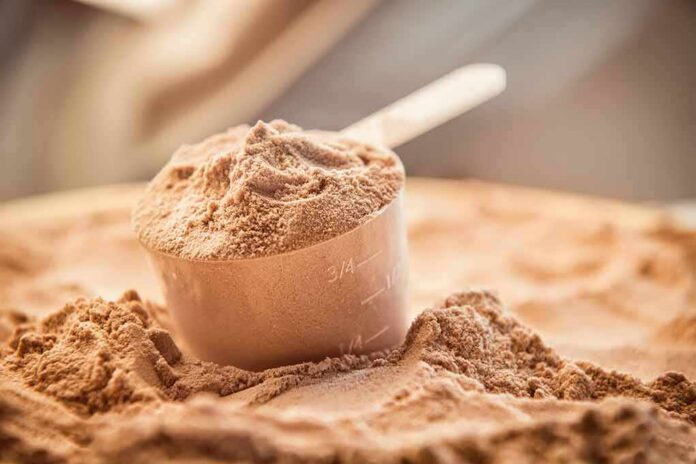 Scoop of chocolate protein powder in a measuring cup