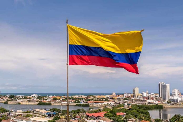 shutterstock_466824740 Colombian flag waving over a coastal city skyline