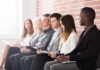 Job candidates seated in a row against a brick wall