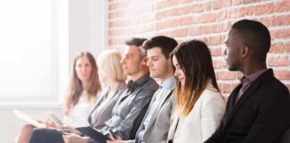 Job candidates seated in a row against a brick wall