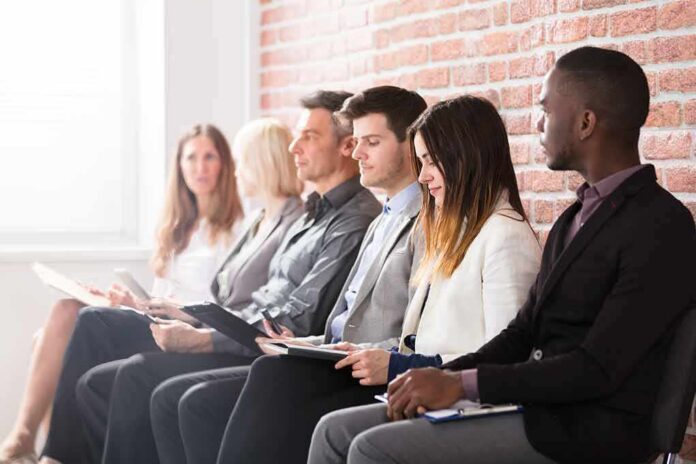 Job candidates seated in a row against a brick wall