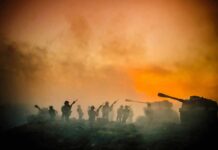 Toy soldiers and tanks silhouetted against an orange smoky sky