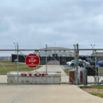 Chain-link fence with Restricted Area Stop No Photography sign.