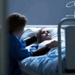 NHS Red Alert: Sickle Care Nears Brink Patient in hospital bed with visitor holding their hand