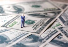 Trump Demands Cuts – Inflation Standoff Jolts Main Street Miniature businessman standing on US dollar bills