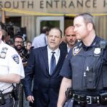 Harvey Weinstein walks outside a courthouse surrounded by police officers