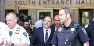 Harvey Weinstein walks outside a courthouse surrounded by police officers