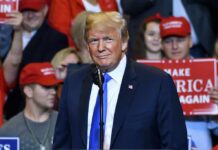 Donald Trump at a rally speaking at a microphone