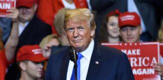 Donald Trump at a rally speaking at a microphone