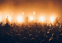 Burning Man Tightens Consent, Chaos Looms? Rock band performing on stage with bright backlights and cheering crowd