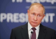 Glorious Gains? ISW Torpedoes Putin’s Victory Hype man in suit at podium with microphone