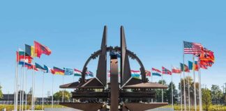 NATO emblem sculpture surrounded by member flags