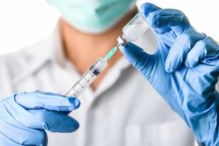 Healthcare worker drawing vaccine from vial with syringe