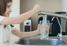 Girl filling a glass with water at a kitchen sink