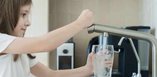 Girl filling a glass with water at a kitchen sink