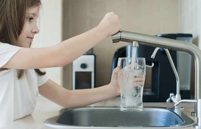 Girl filling a glass with water at a kitchen sink