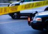 Police cars behind yellow caution tape at a street scene