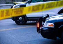 False Alert: Glitch Triggers Gunpoint Takedown Police cars behind yellow caution tape at a street scene