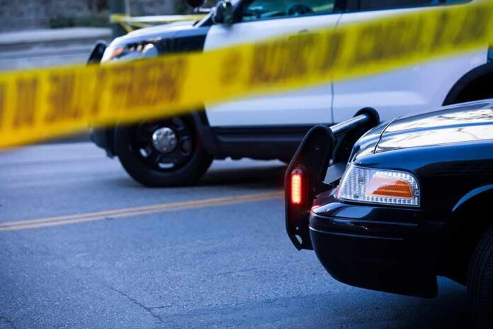 shutterstock_2097855037 Police cars behind yellow caution tape at a street scene