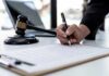 Botched Case, Buried Memo – Cover-Up or Chaos? Hand signing legal document beside gavel and laptop