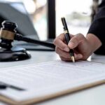 Botched Case, Buried Memo – Cover-Up or Chaos? Hand signing legal document beside gavel and laptop