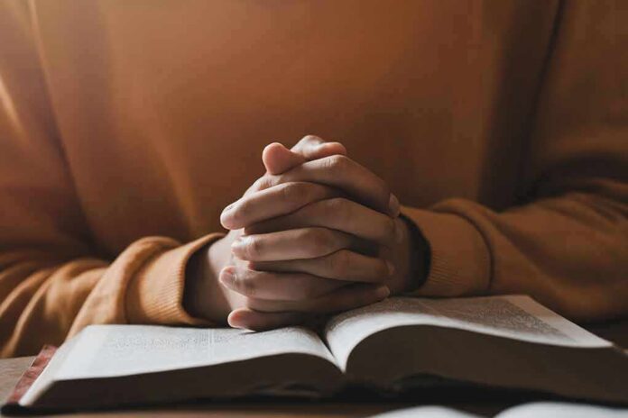 shutterstock_2146022413 Hands clasped over an open book