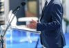 Massie Springs Shock Impeachment Vote Speaker in a suit at a podium with microphone