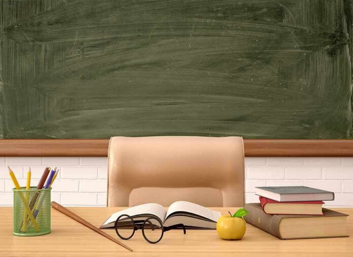 Teacher's desk with books, apple, and chalkboard