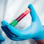 Gloved hand holding a blood sample tube