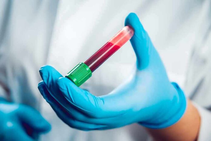 shutterstock_326298614 Gloved hand holding a blood sample tube