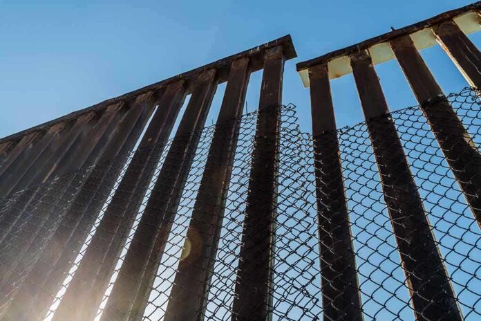 shutterstock_502528507 Steel border fence with chain-link mesh under blue sky