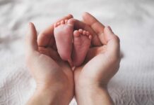 Adult hands cradling newborn baby feet