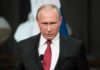 Vladimir Putin speaking at a podium with a microphone