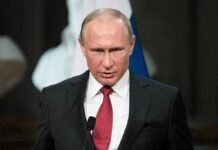 Vladimir Putin speaking at a podium with a microphone