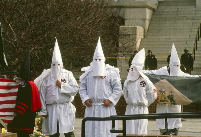 ku klux klan members in white robes and hoods at a public gathering