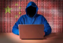 Hooded figure using a laptop