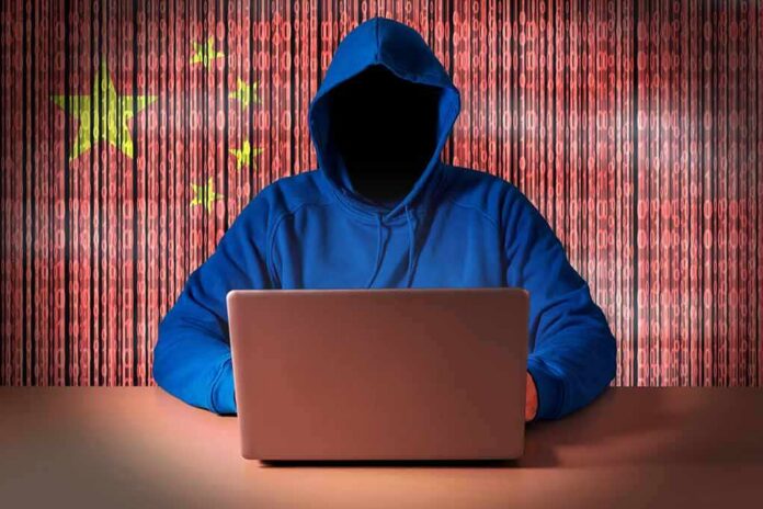 Hooded figure using a laptop