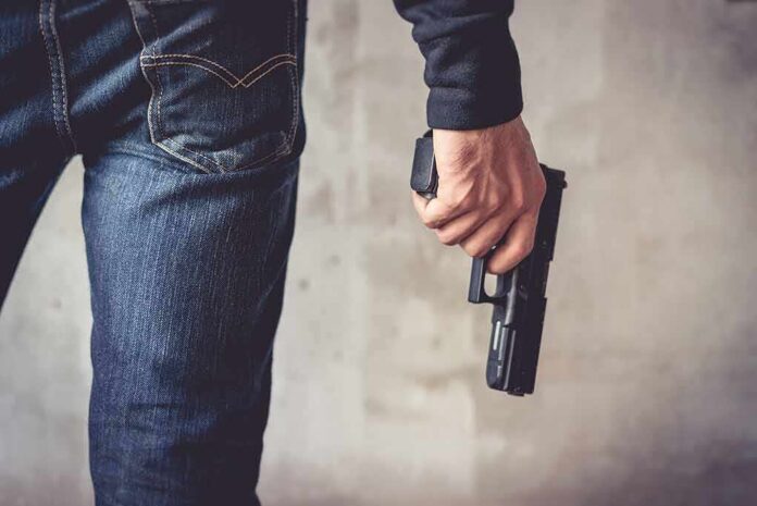 shutterstock_1035985711 person holding a handgun by their side
