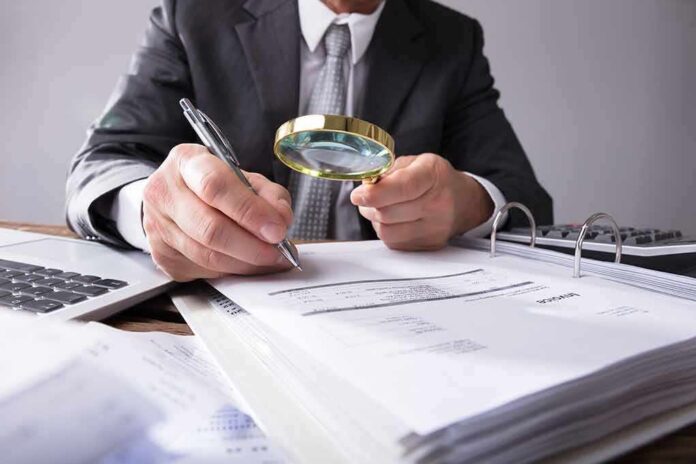 shutterstock_1058554241 Businessperson examining invoices with a magnifying glass