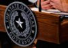 Blue Surge Targeting Abbott’s Firewall Texas governor seal on wooden podium