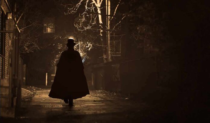 Silhouette of a person in a long coat and hat walking down a dimly lit alley