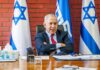 Election Crunch: Netanyahu Seeks Trump Megaphone man in suit seated at a desk with Israeli flags behind him