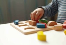 Child hand placing wooden shapes in a puzzle board