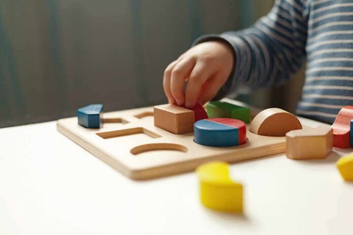shutterstock_1731101767 Child hand placing wooden shapes in a puzzle board